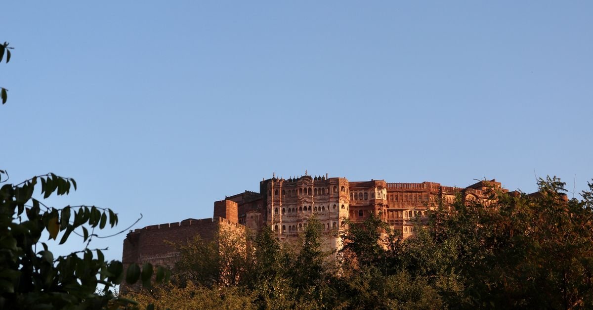 Scenic view of Mehrangarh Fort surrounded by lush greenery under a clear blue sky in Jodhpur, India.