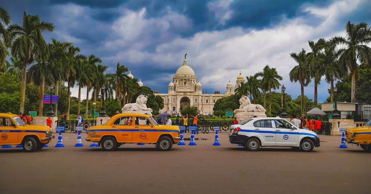 Vibrant city scene with taxis and Victoria Memorial in Kolkata, India.