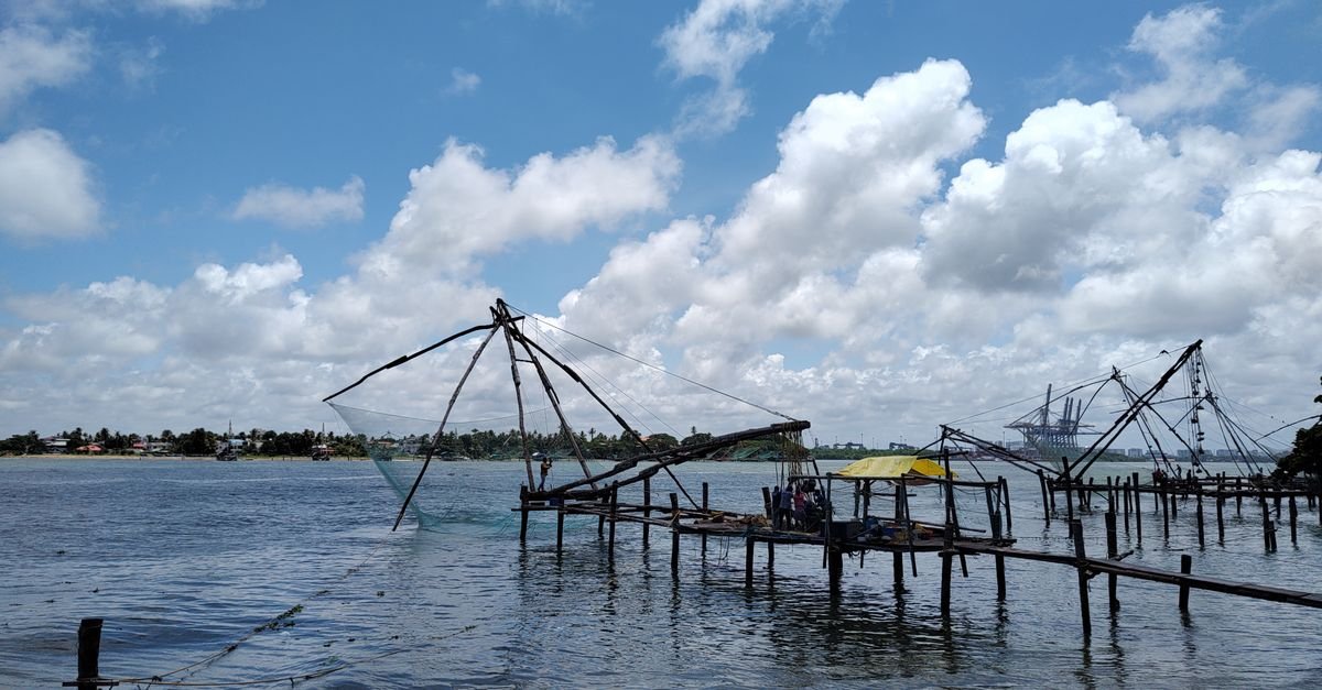 Traditional Chinese fishing nets silhouetted against a clear blue sky in Kerala.
