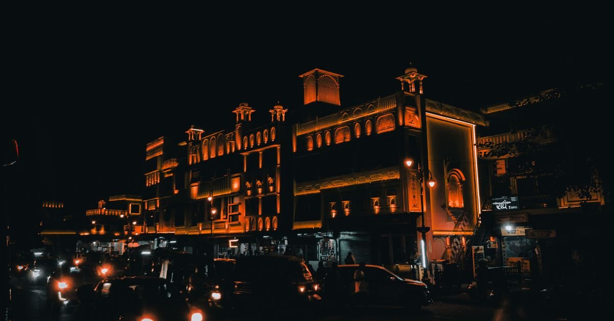 Orange-lit buildings and bustling street traffic form a cinematic night view in India.