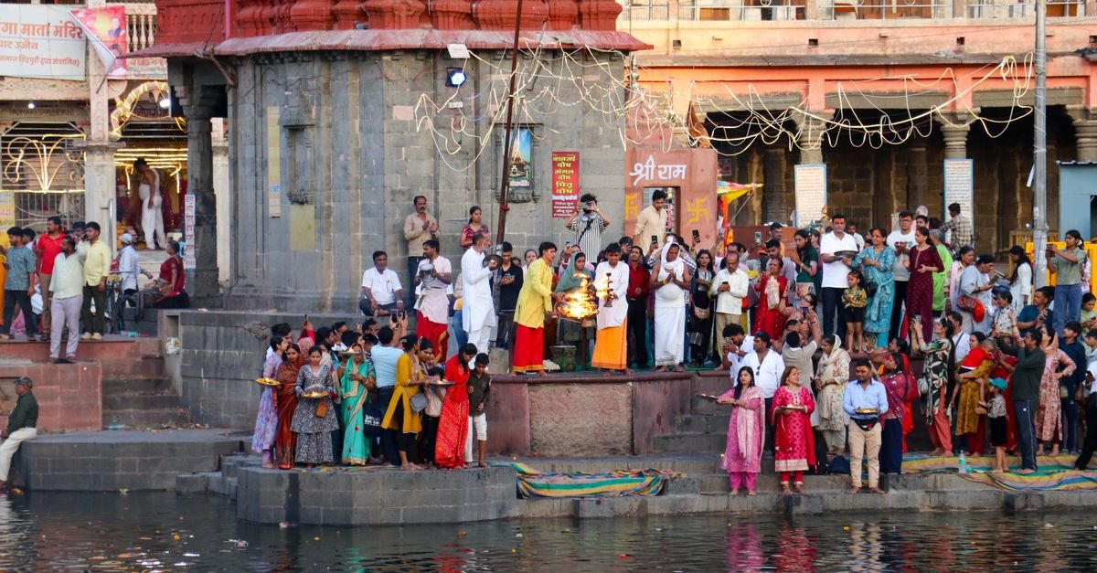 A vibrant spiritual gathering for Aarti at a temple ghat in Ujjain, India surrounded by devotees during sunset.