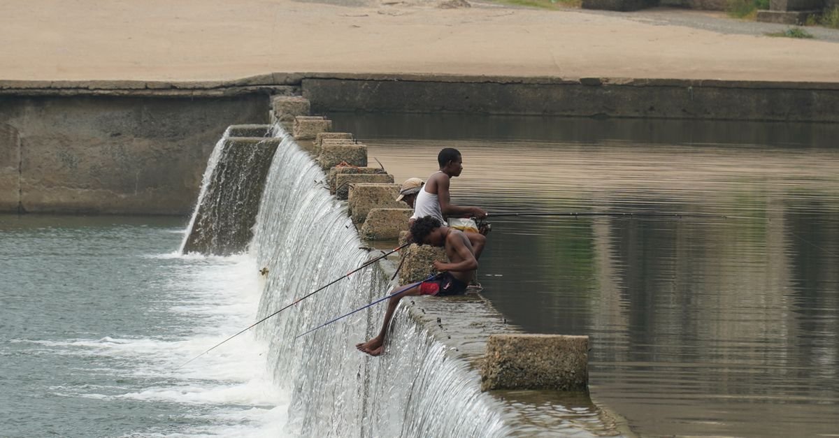 Three men fishing on the Kharkai River dam in Jamshedpur, India.