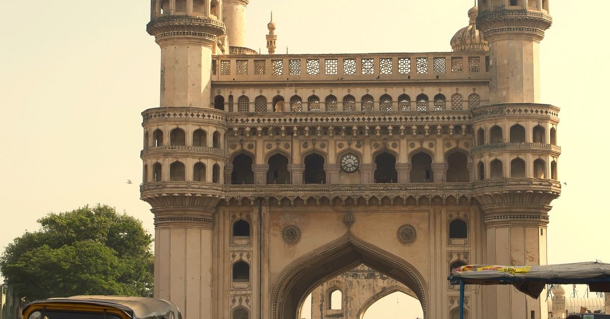 Street view of Charminar in Hyderabad with people, vehicles, and vendors, reflecting vibrant Indian culture.