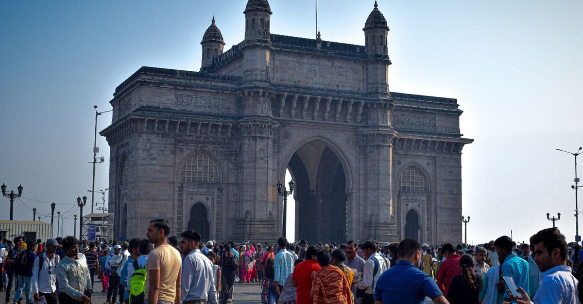 Vibrant crowd gathered at the famous Gateway of India in Mumbai, India during the day.